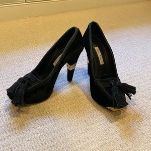 Black velvet heels with tassels and gold accent.